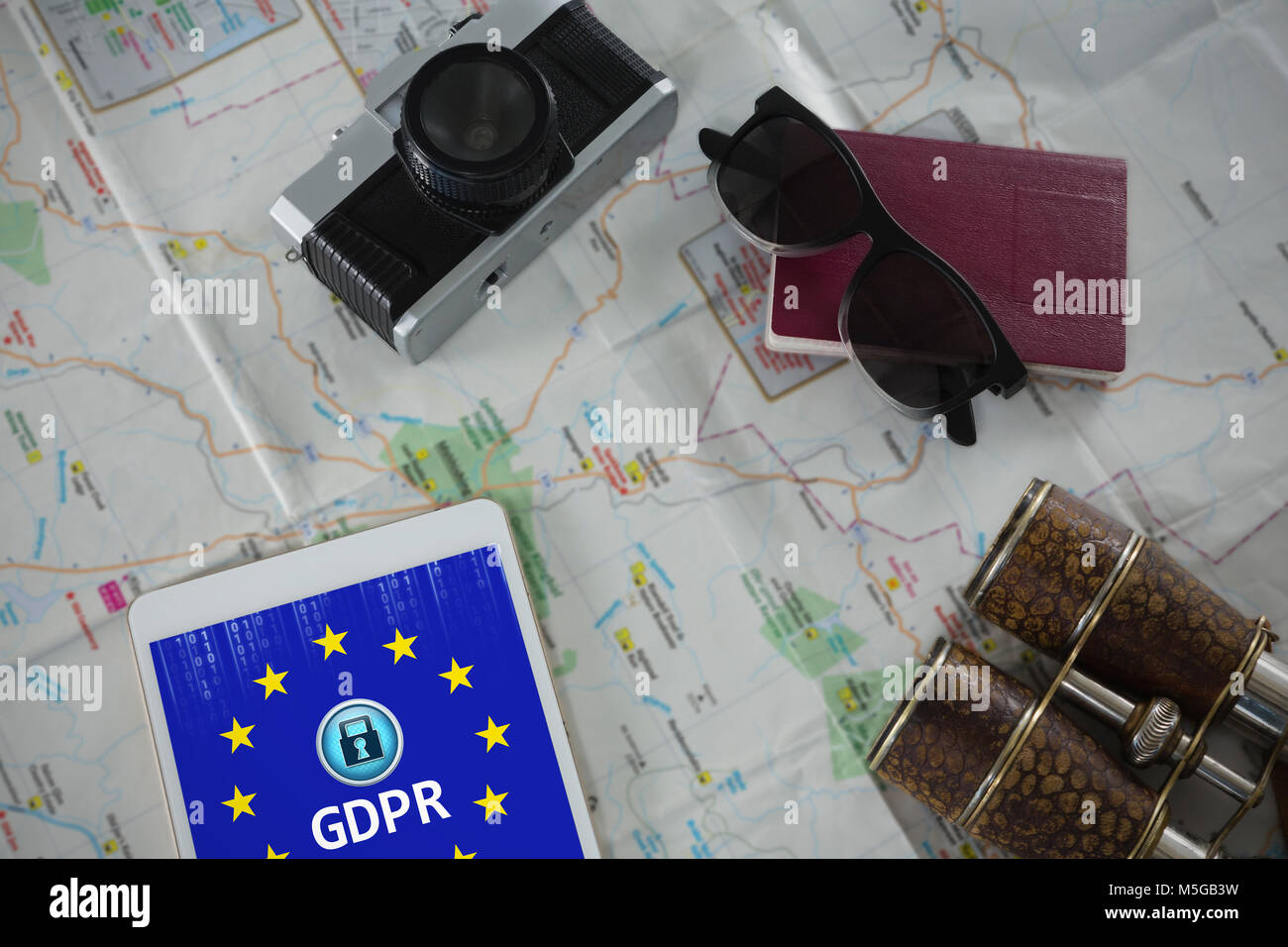 Image composite de passeport, appareil photo, jumelles et tablette numérique sur la carte Banque D'Images