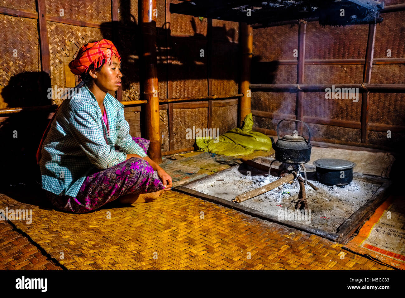 Les agriculteurs d'une femme est assise à l'endroit du feu dans sa maison de bambou dans un village dans les collines de la région tribale Banque D'Images