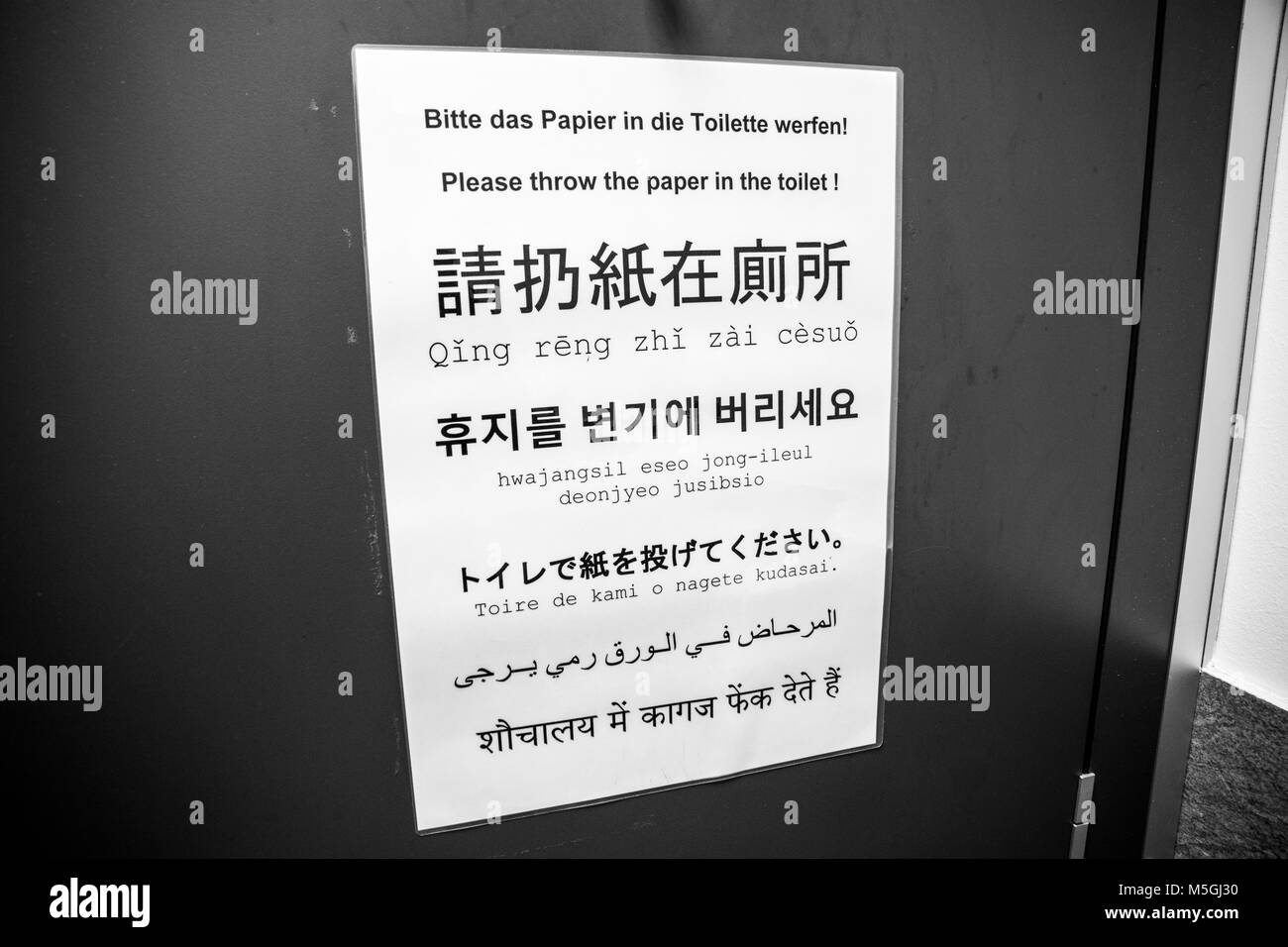 Inscrivez-vous à l'intérieur d'une salle de bains de dire aux gens de jeter le papier dans les toilettes. Rédigé en allemand, anglais, chinois, japonais, coréen, arabe et hindi Banque D'Images