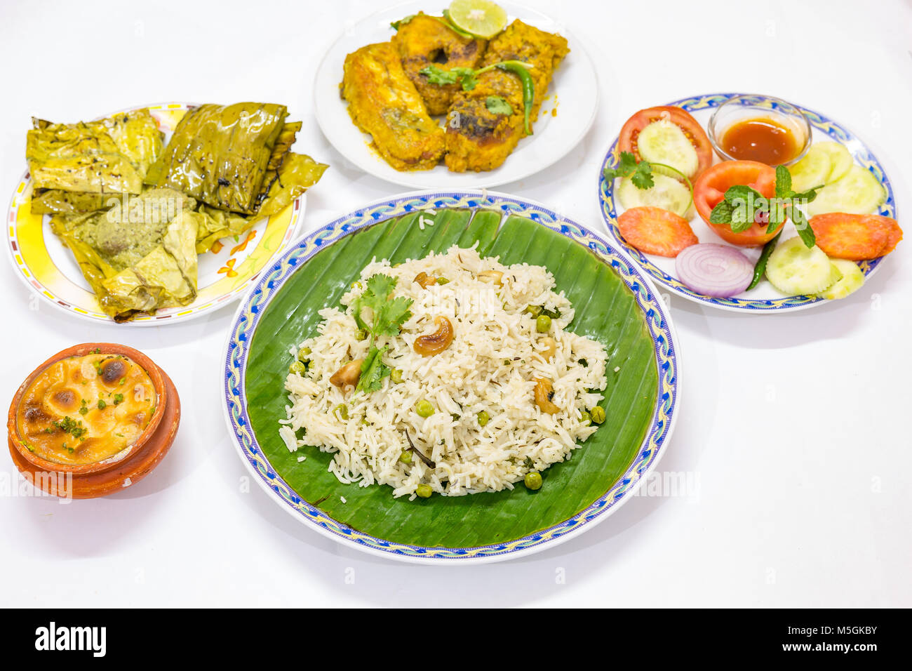 Populaires de délicieux repas de cuisine indienne Bengali avec riz frit aux légumes , épicé curry de poisson, des salades et un plat sucré. Banque D'Images