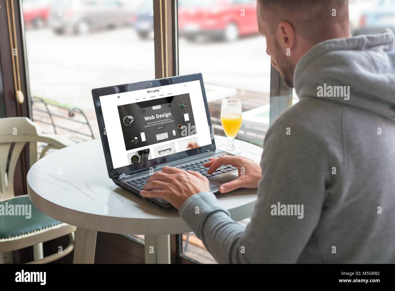 Ouvert aux visiteurs un site web responsable de la société de design sur son ordinateur portable. Café-restaurant dans l'arrière-plan. Banque D'Images