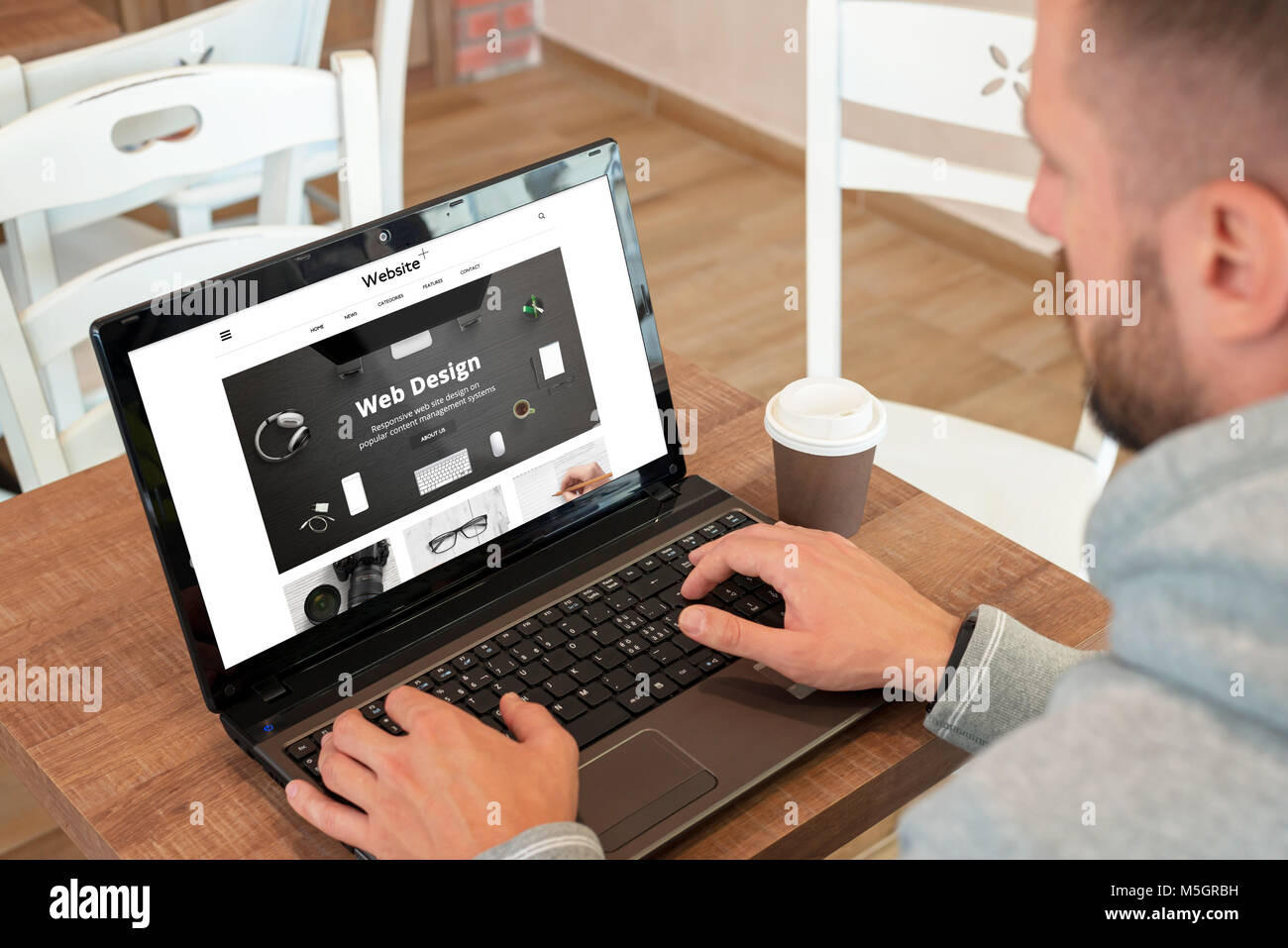 Web design company site web adapté sur écran de l'ordinateur portable. Guy watch site et boire un café. Banque D'Images