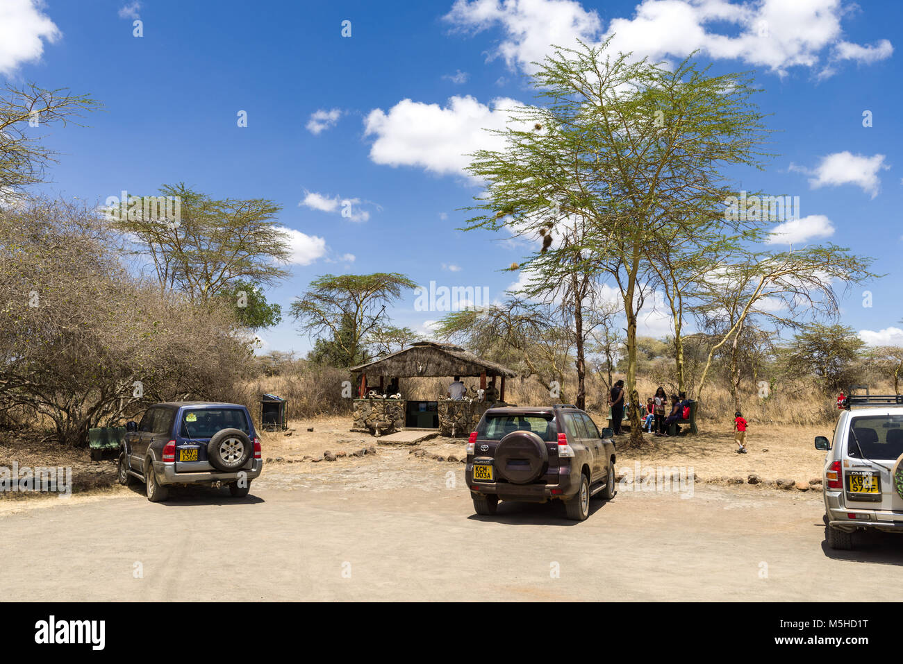 Les véhicules stationnés à l'Hippo piscines parking dans le Parc National de Nairobi avec des gens à l'ombre des arbres, au Kenya Banque D'Images