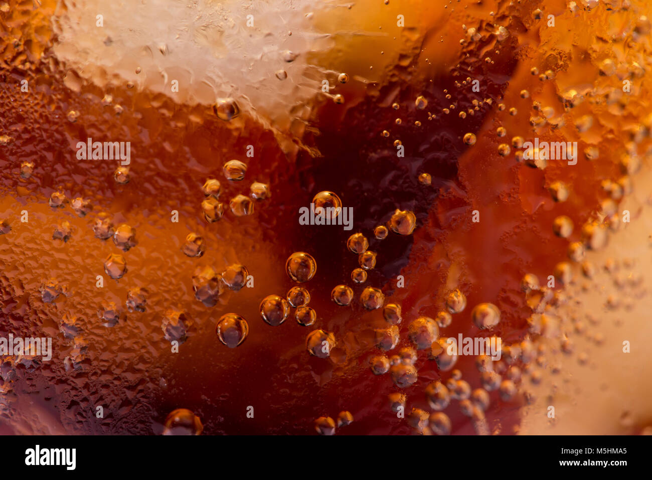 Macro de bulles et de fizz. Un verre de boisson coca avec de la glace Banque D'Images