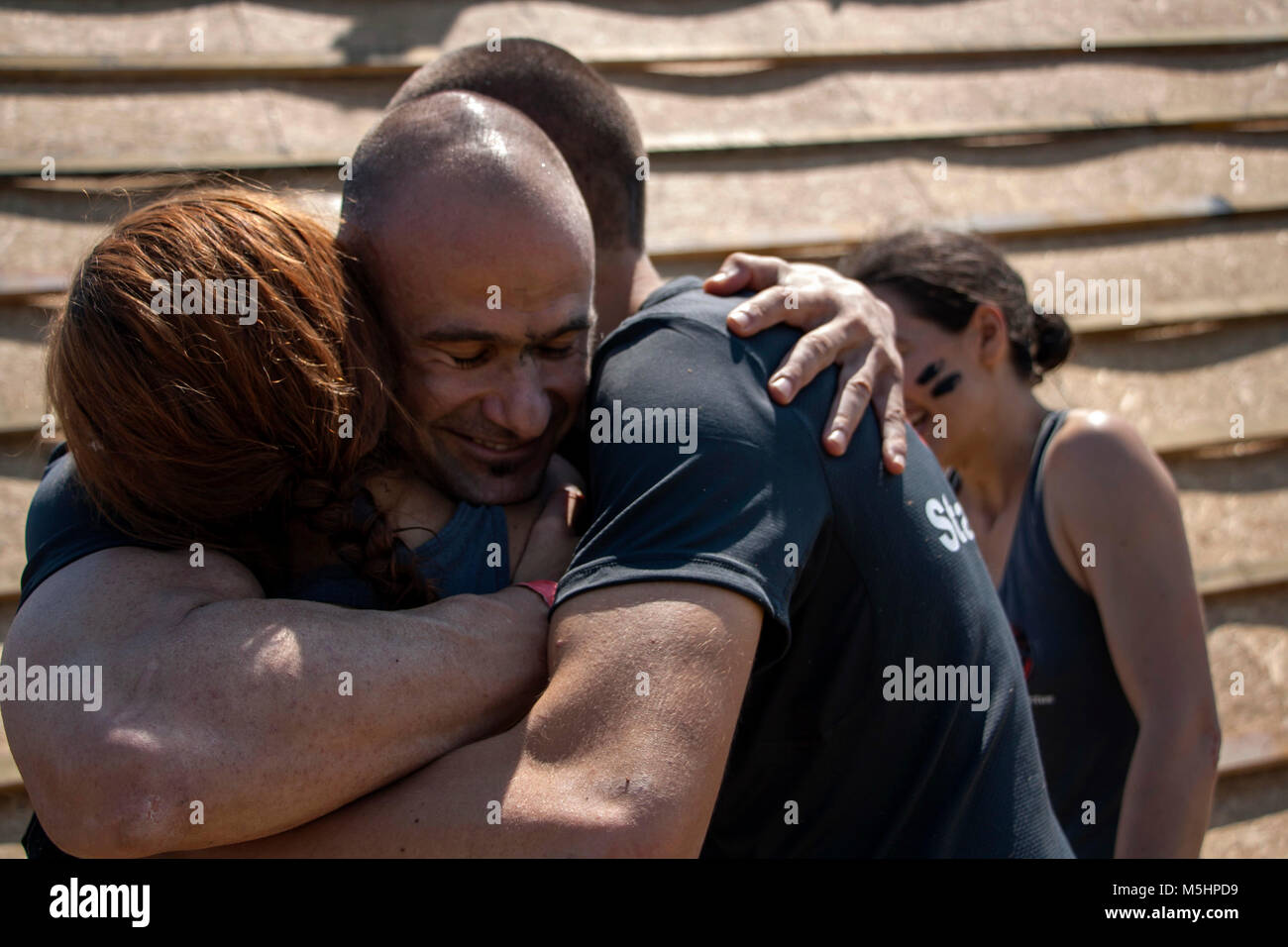 Deux hommes et une femme ayant un friendly hug ensemble après avoir terminé les défis en force race course de la Légion qui s'est tenue à Sofia, Bulgarie le 26 juillet 2014 Banque D'Images