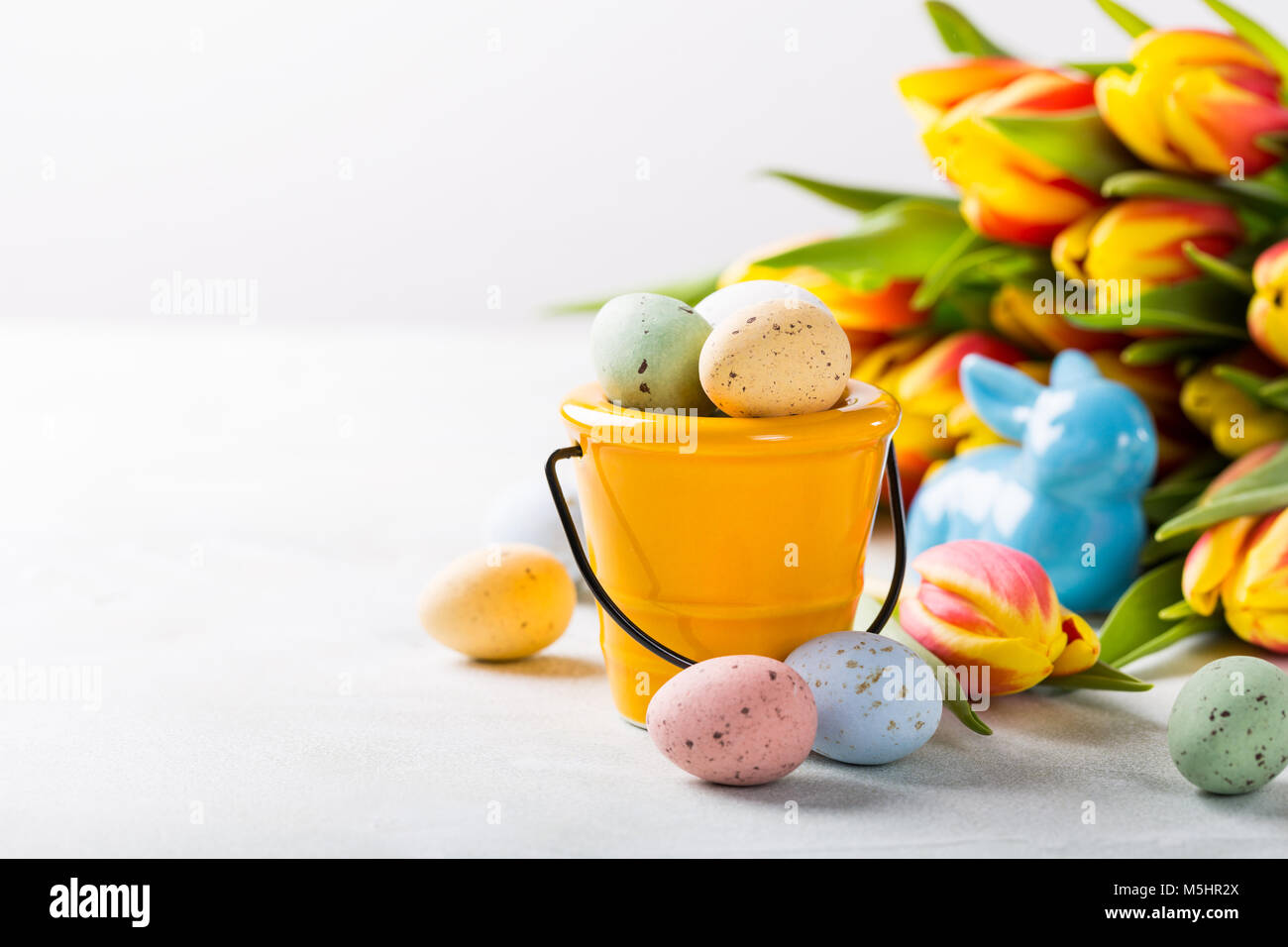 Composition de pâques bonbons colorés avec des oeufs de cailles dans le godet et tulipes fleurs de printemps. Vacances concept avec copie espace. Banque D'Images