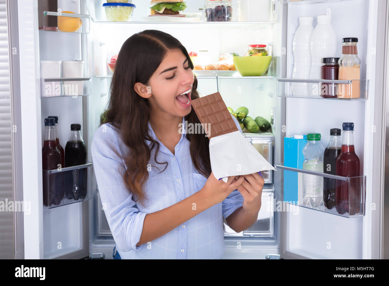 Jeune femme admirant le chocolat dans l'avant du réfrigérateur Banque D'Images