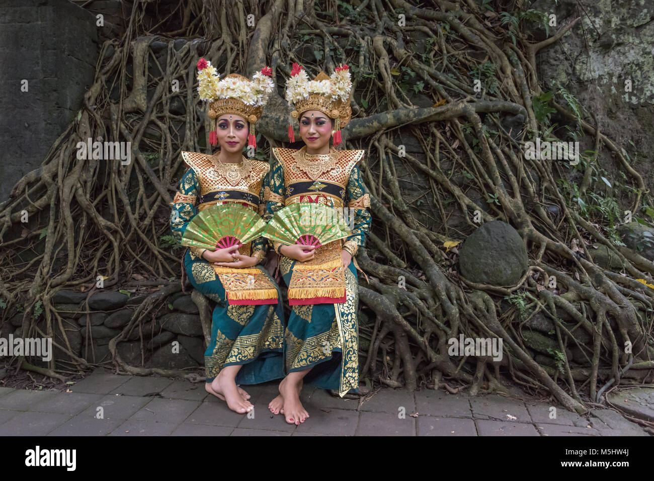 Paire de danseurs en costumes traditionnels balinais avec racines ficus en arrière-plan, Monkey Forest, Ubud, Bali Banque D'Images