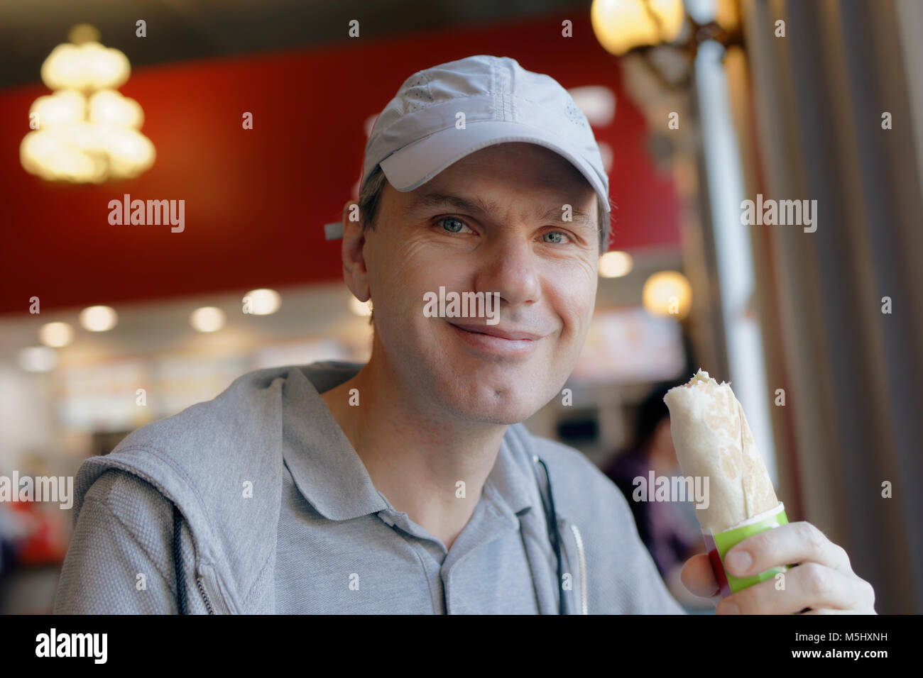 L'homme dans les tenues de rouleau de manger dans un fast-food restaurant Banque D'Images
