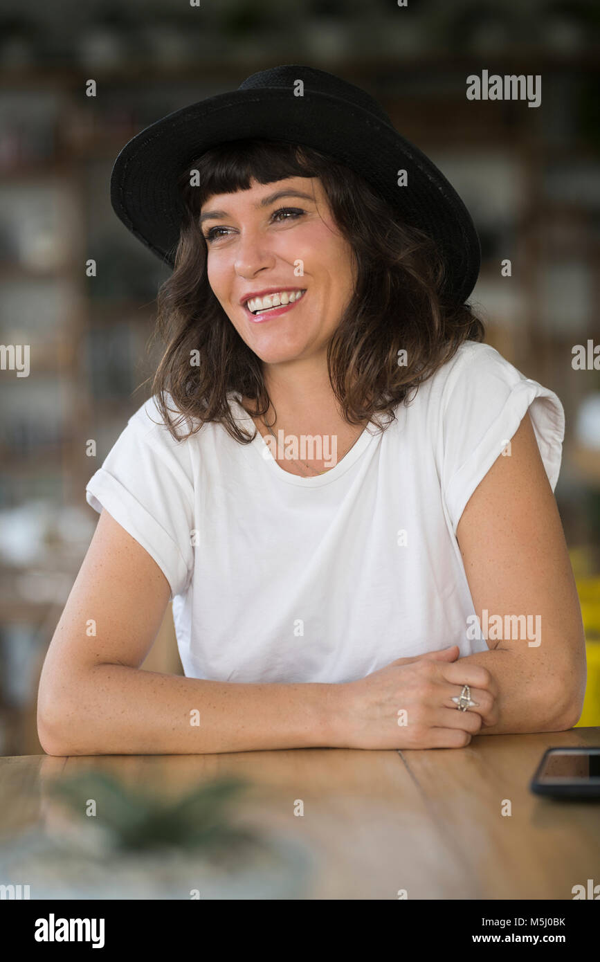 Portrait of smiling woman with hat dans un café Banque D'Images