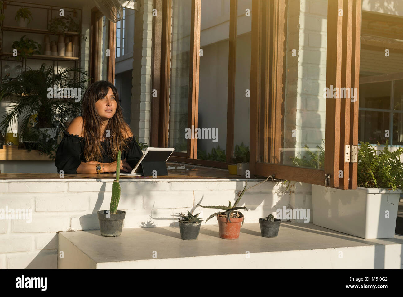 Pensive woman with tablet sitting in a cafe Banque D'Images