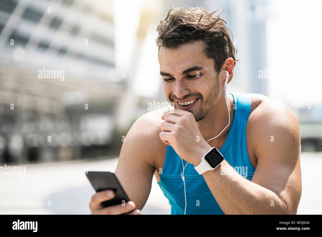 Runner wearing earphones, consultation des messages sur son smartphone Banque D'Images