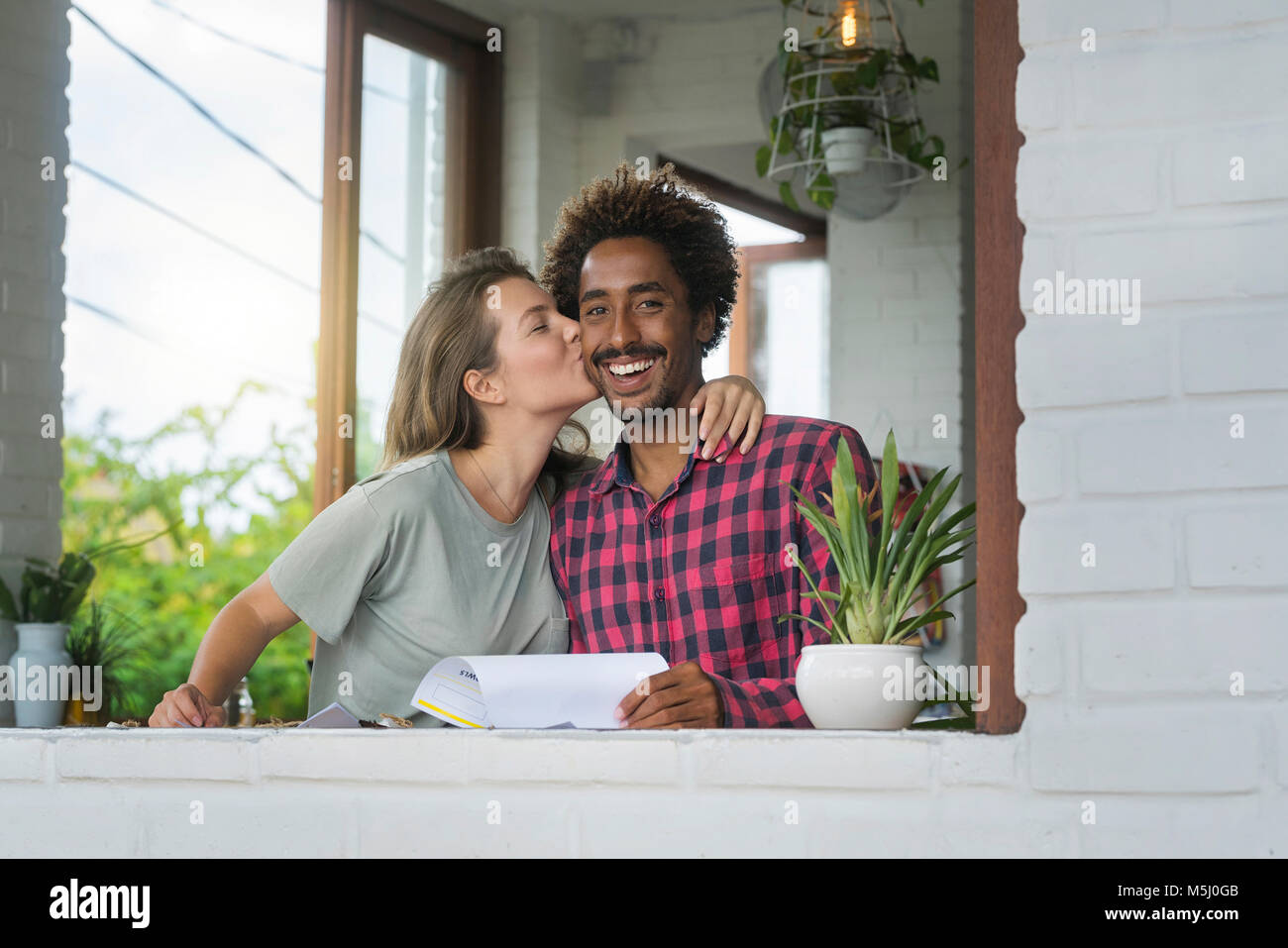 Woman kissing her boyfriend on cheek in cafe Banque D'Images