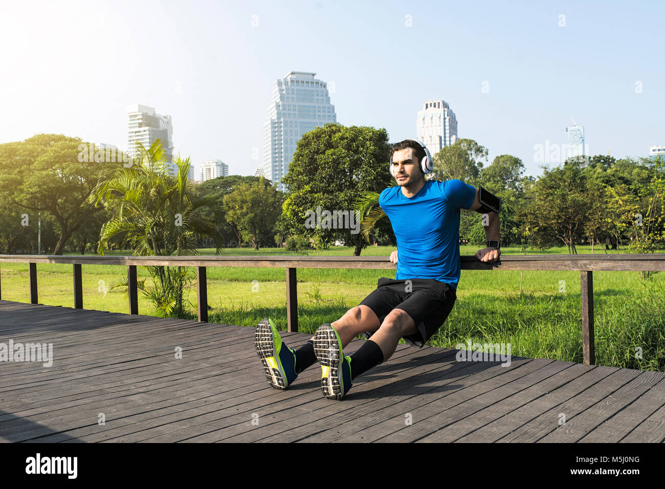 Runner avec un casque faisant push-ups en parc urbain Banque D'Images