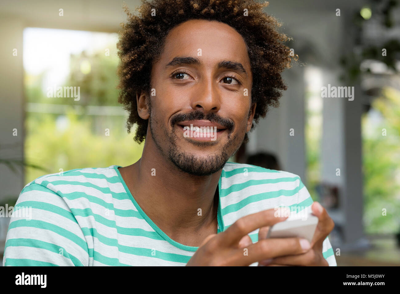 Smiling man with smartphone dans un café Banque D'Images