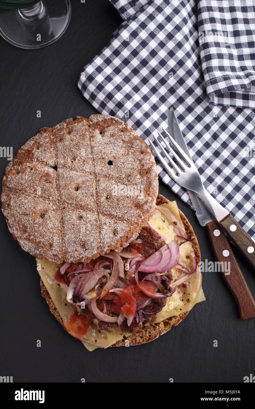 Dirty burger avec fromage, pain de seigle, oignon rouge, sauce tomate et libre Banque D'Images