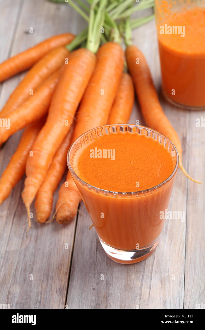 Tasse de jus de carotte et légumes frais sur une table rustique Banque D'Images