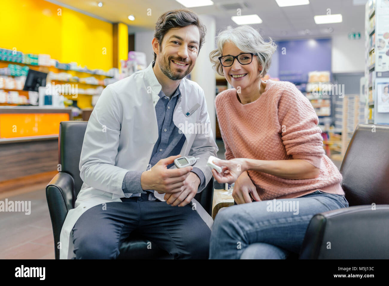Portrait of smiling pharmacien et client avec compteur de sucre de sang en pharmacie Banque D'Images