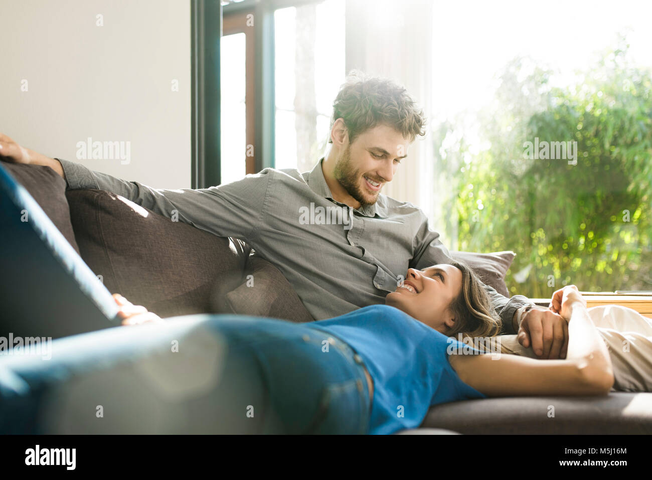 Affectionate couple smiling on sofa at home Banque D'Images