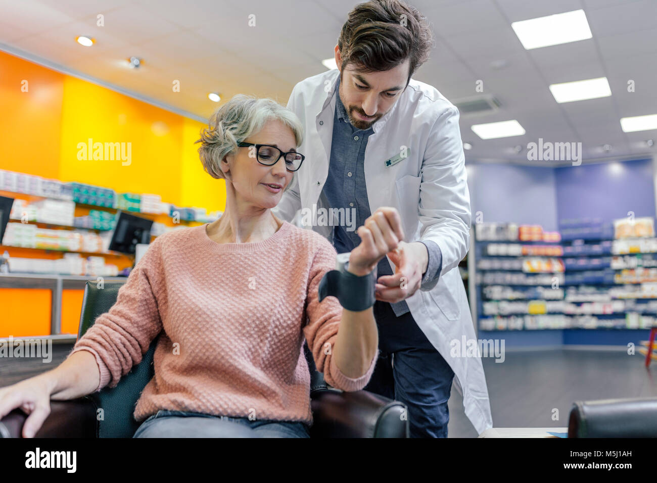 Pharmacien de prendre la tension artérielle de client en pharmacie Banque D'Images