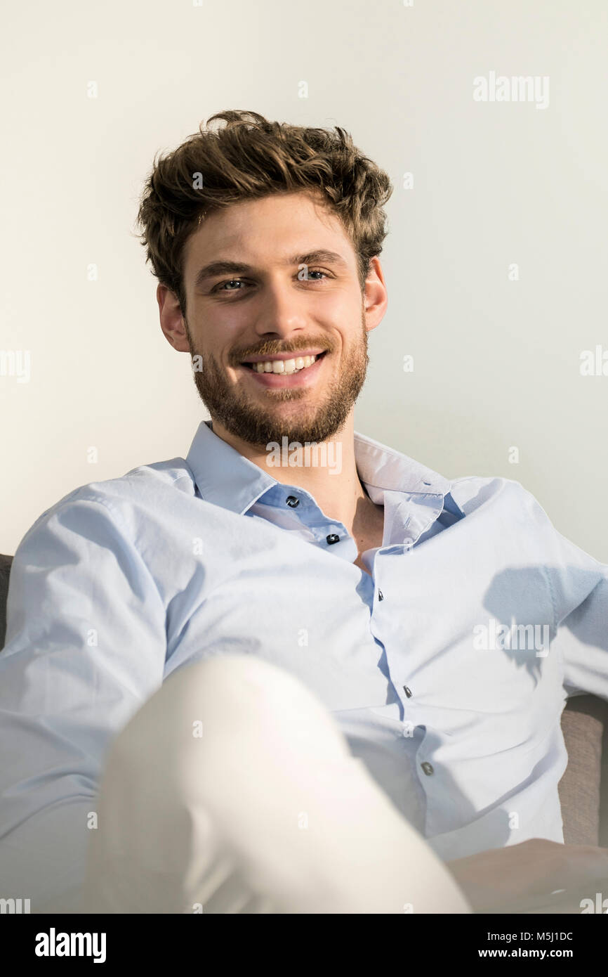 Portrait of smiling young man sitting on couch Banque D'Images
