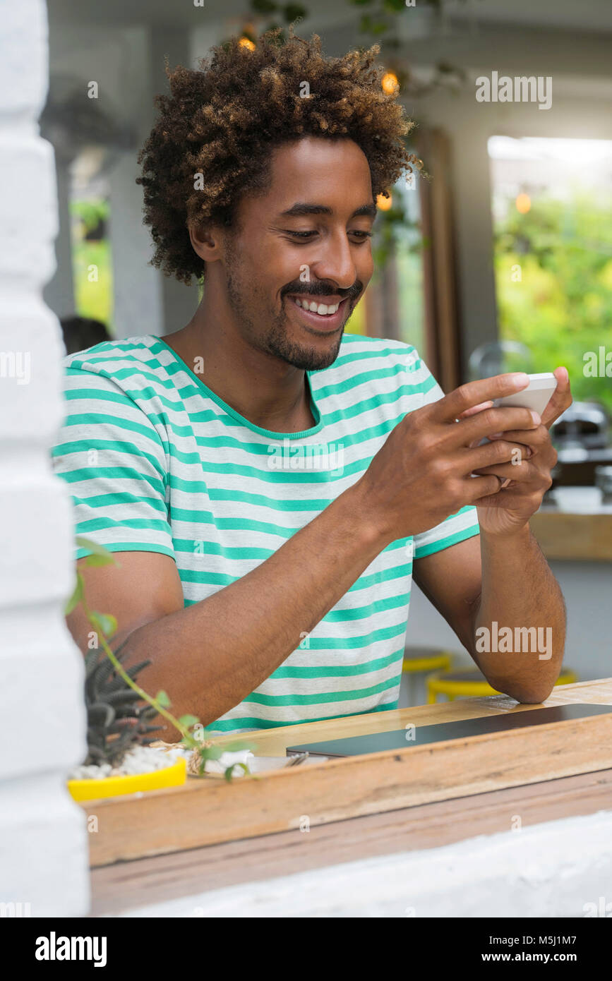 Smiling man contrôler son smartphone au bar dans un café Banque D'Images
