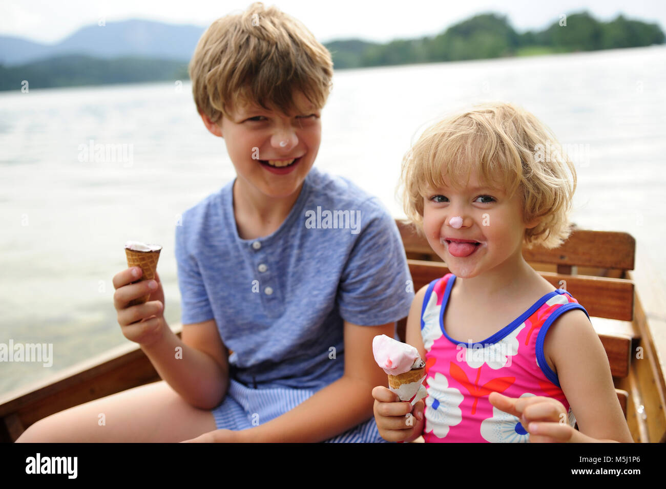 Portrait de petite fille assise en bateau à rames avec son frère manger icecream Banque D'Images