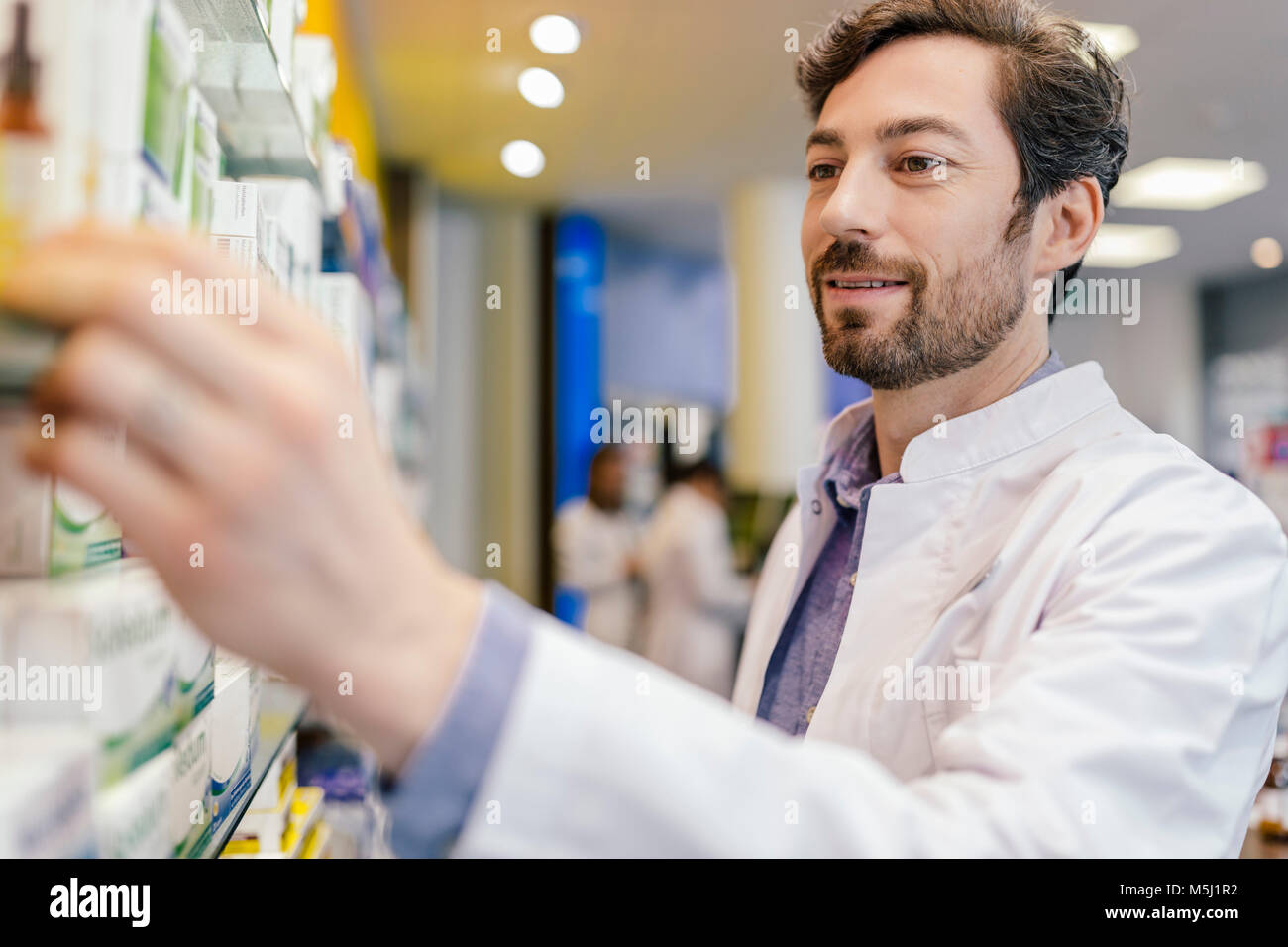 Pharmacien prenant la médecine à partir de la tablette dans la pharmacie Banque D'Images