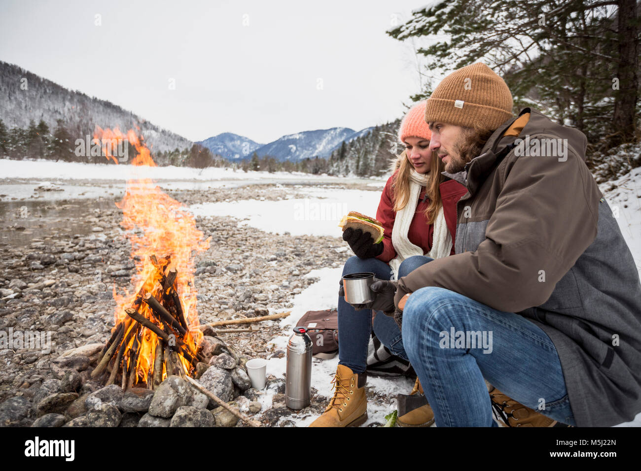 Couple sur un voyage en hiver d'avoir une pause au camp fire Banque D'Images