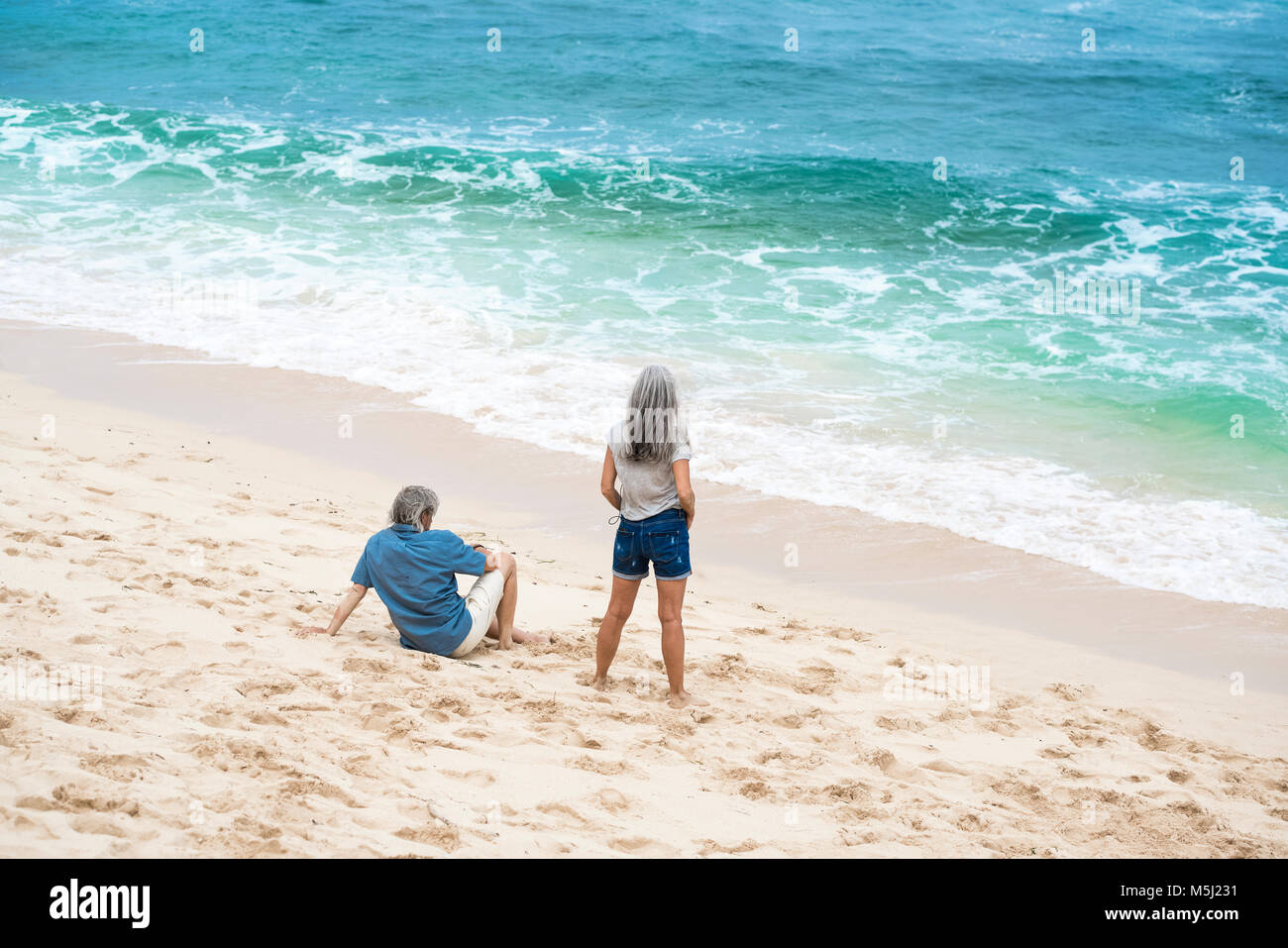 Couple sur la plage face à la mer Banque D'Images