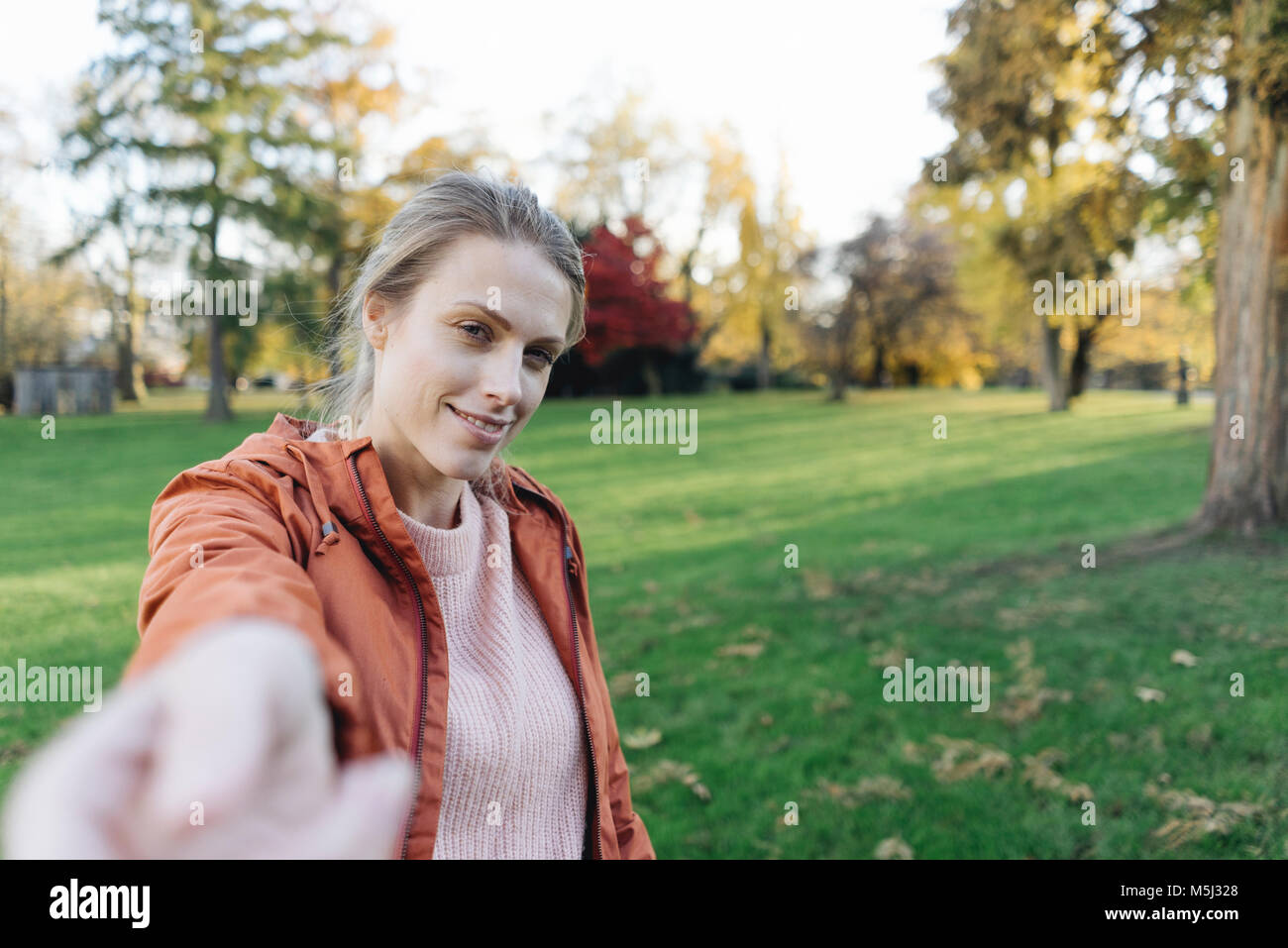 Portrait of young woman reaching out main dans autumnal park Banque D'Images
