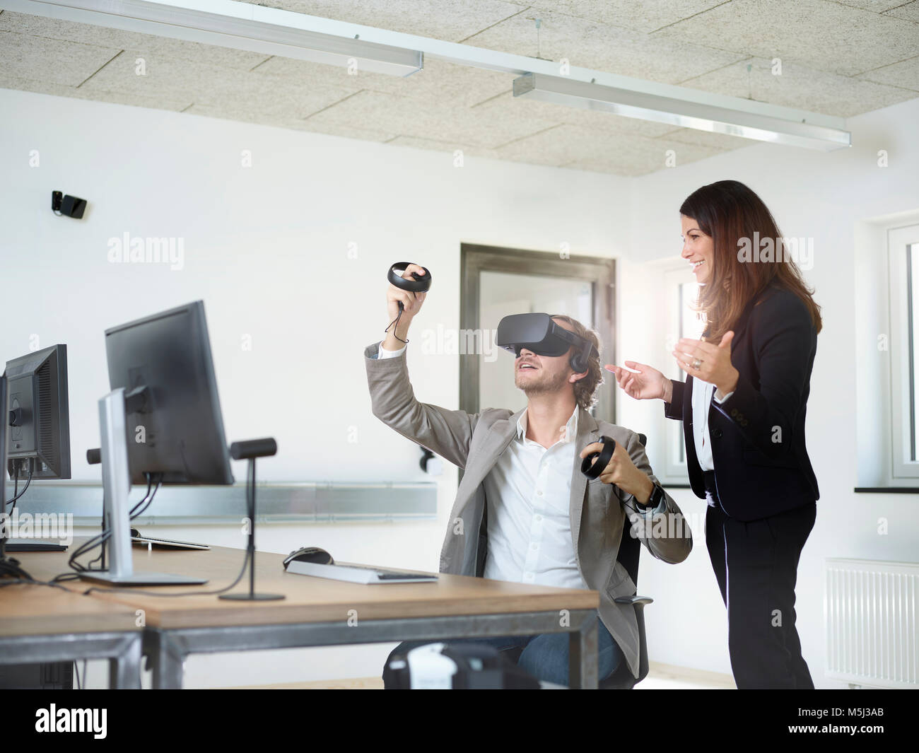 Femme avec homme portant lunettes VR in office Banque D'Images