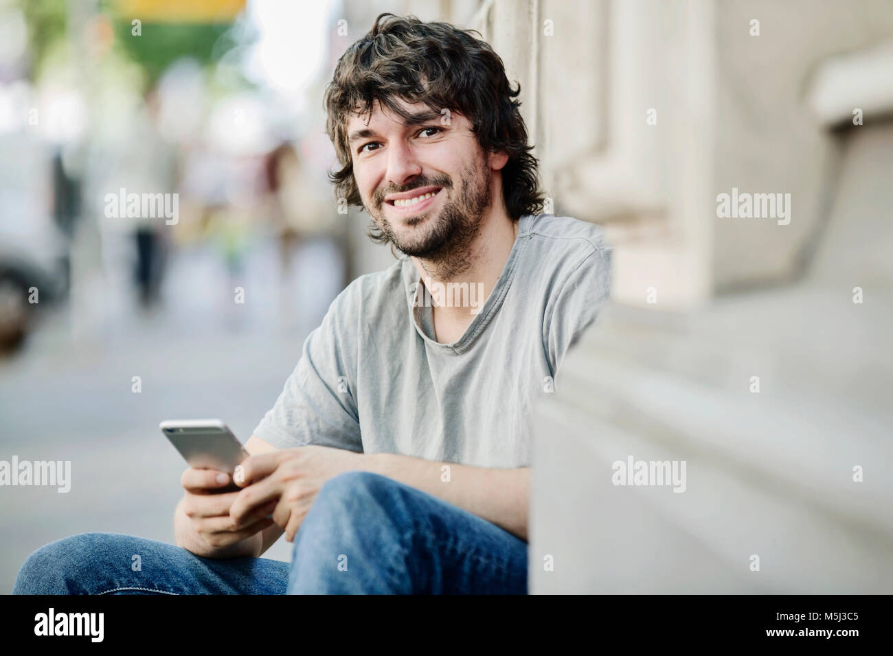 Portrait of smiling young man with cell phone outdoors Banque D'Images