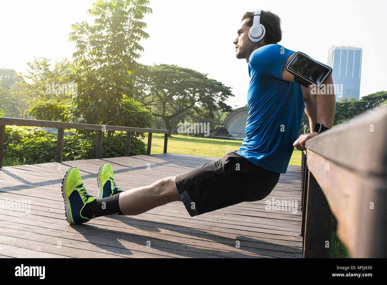 Runner avec un casque faisant push-ups en parc urbain Banque D'Images