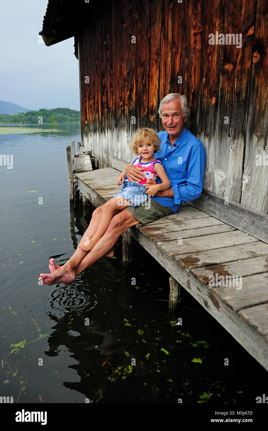 Petite fille assise avec son grand-père on jetty en été Banque D'Images