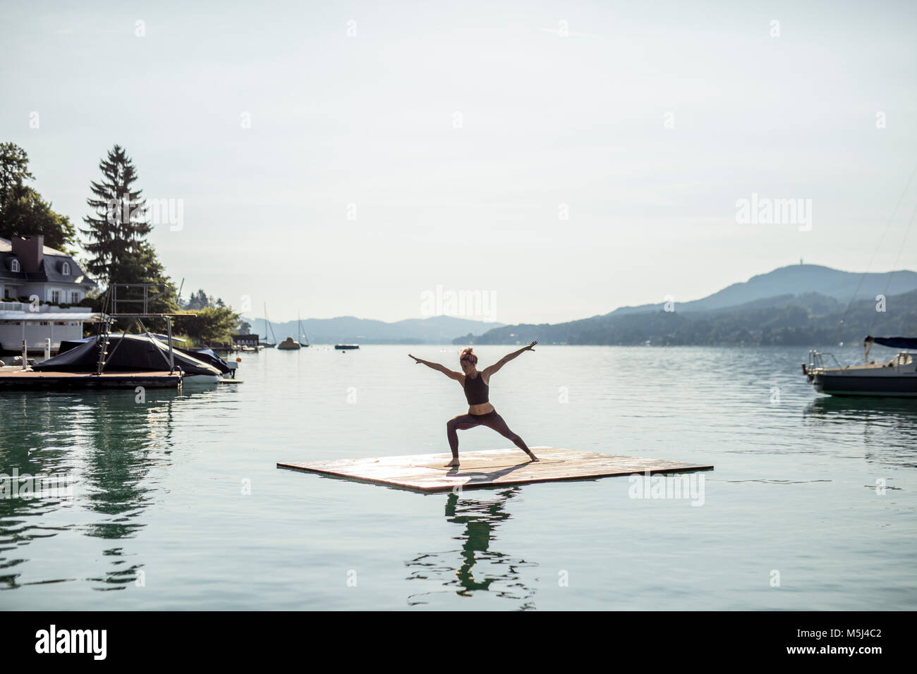 Woman practicing yoga on raft dans un lac Banque D'Images