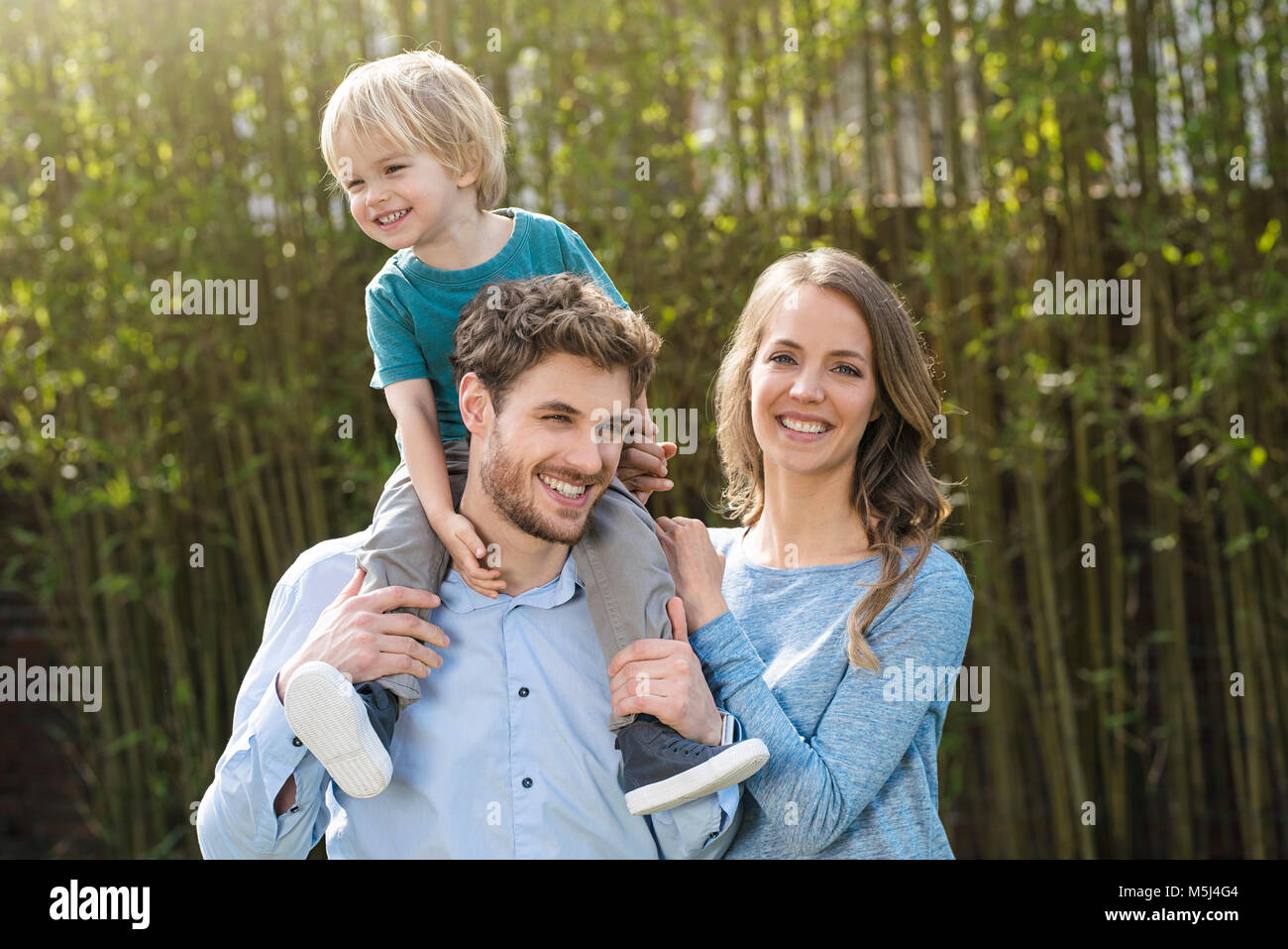 Portrait de famille heureuse dans un jardin en face de plantes de bambou Banque D'Images
