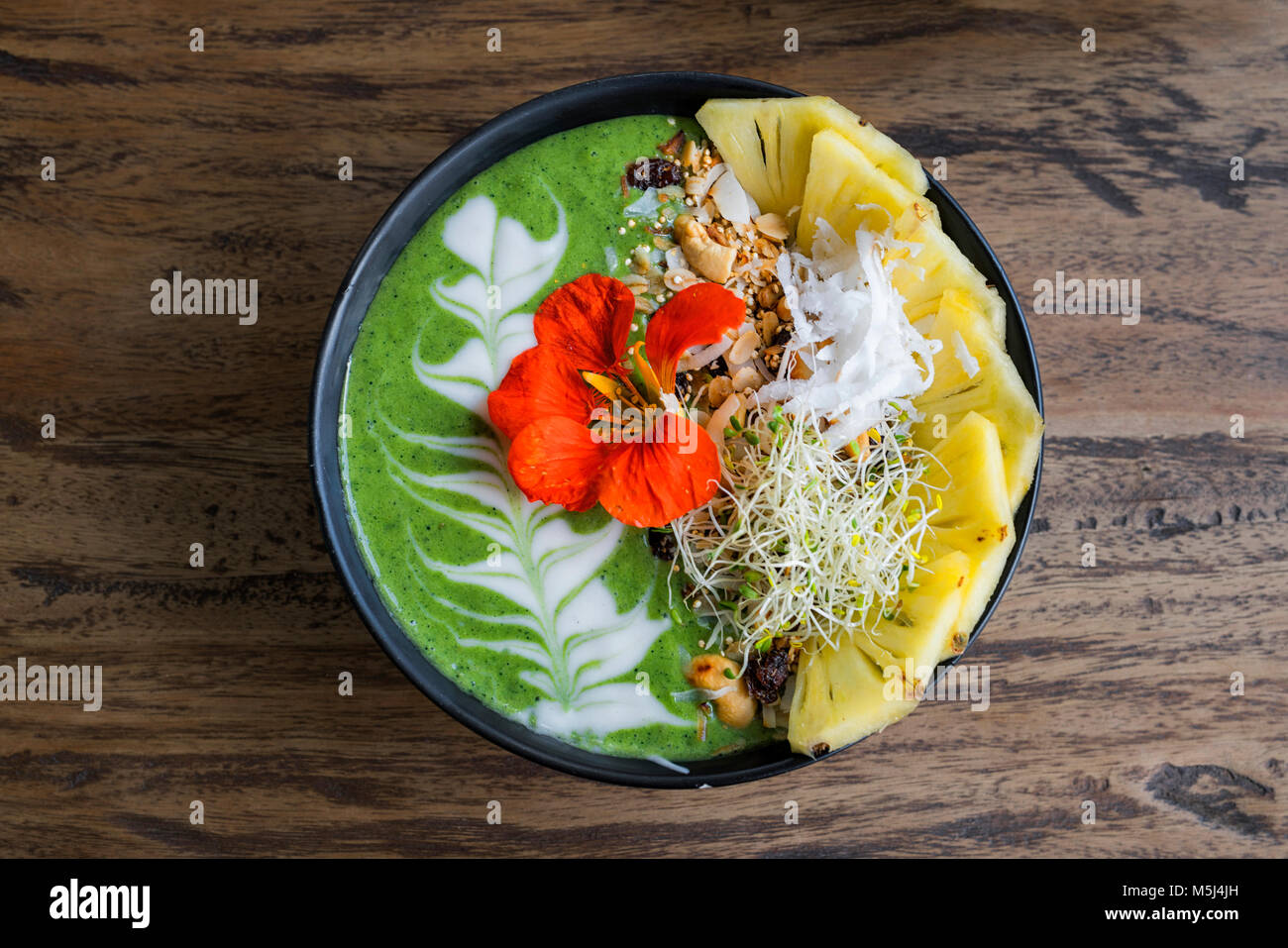 Smoothie vert décoré bol avec l'ananas et de fleurs comestibles Banque D'Images