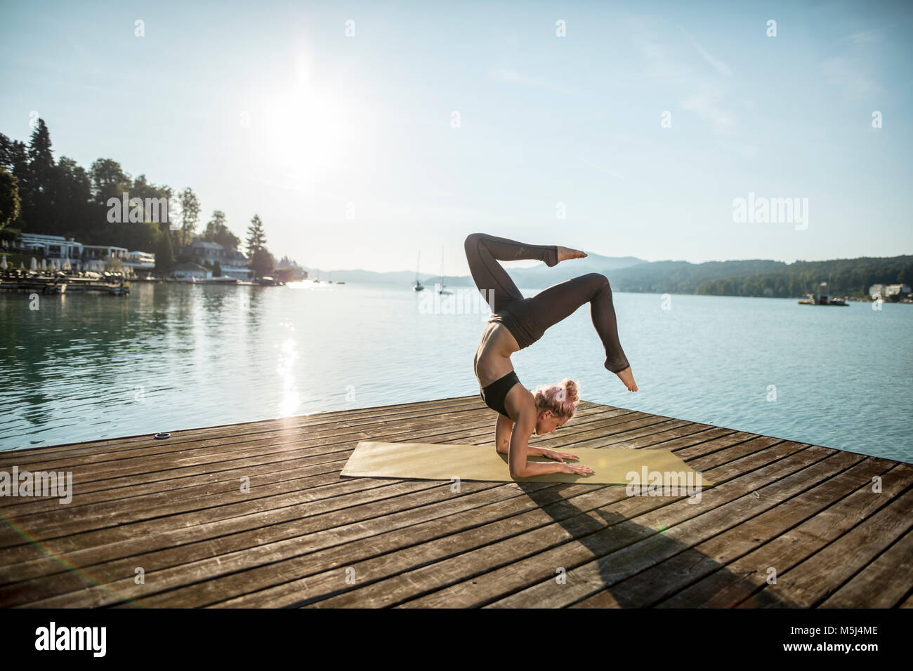 Woman practicing yoga on jetty at un lac Banque D'Images