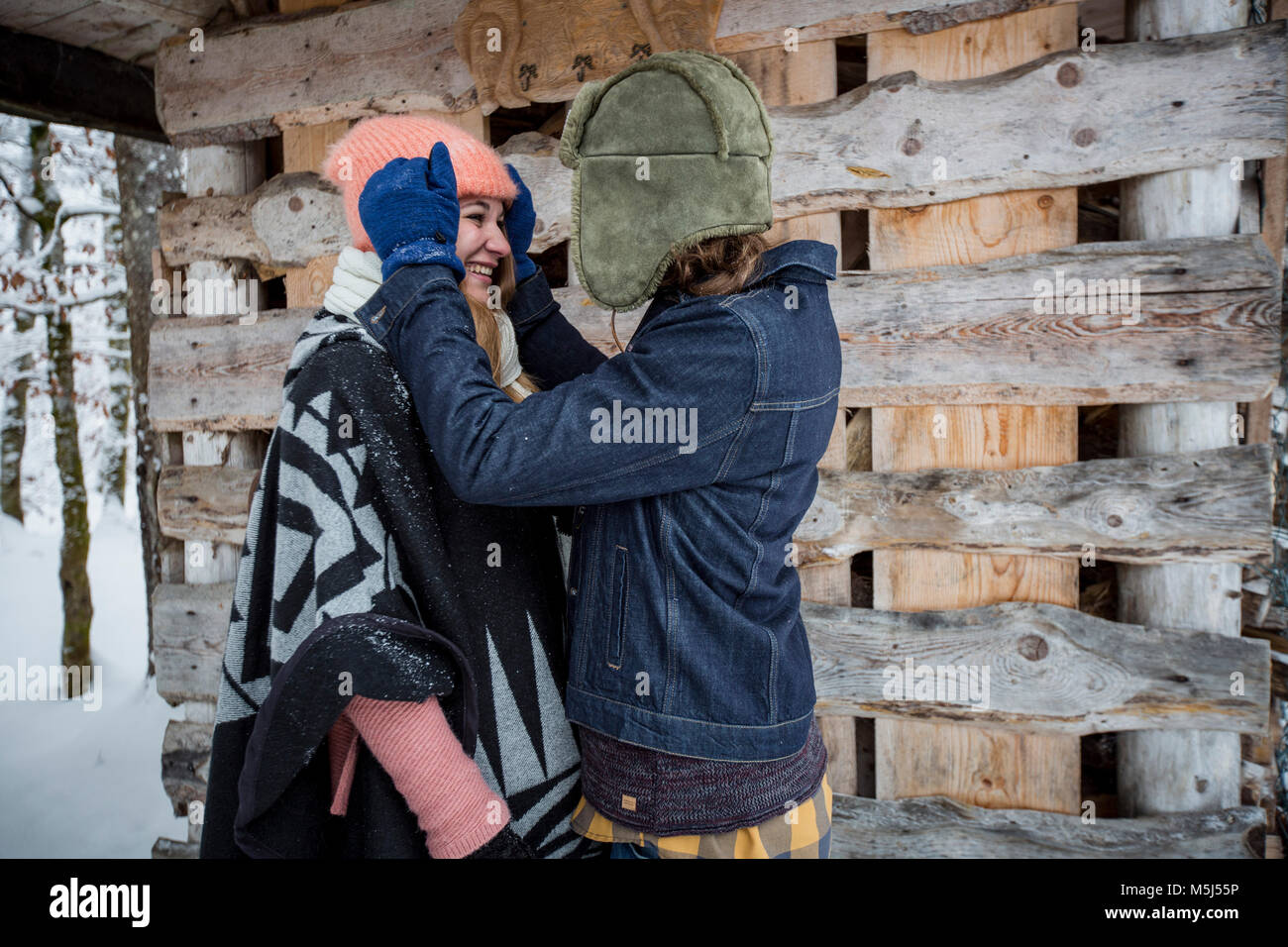 Couple heureux en face de pile de bois à l'extérieur en hiver Banque D'Images