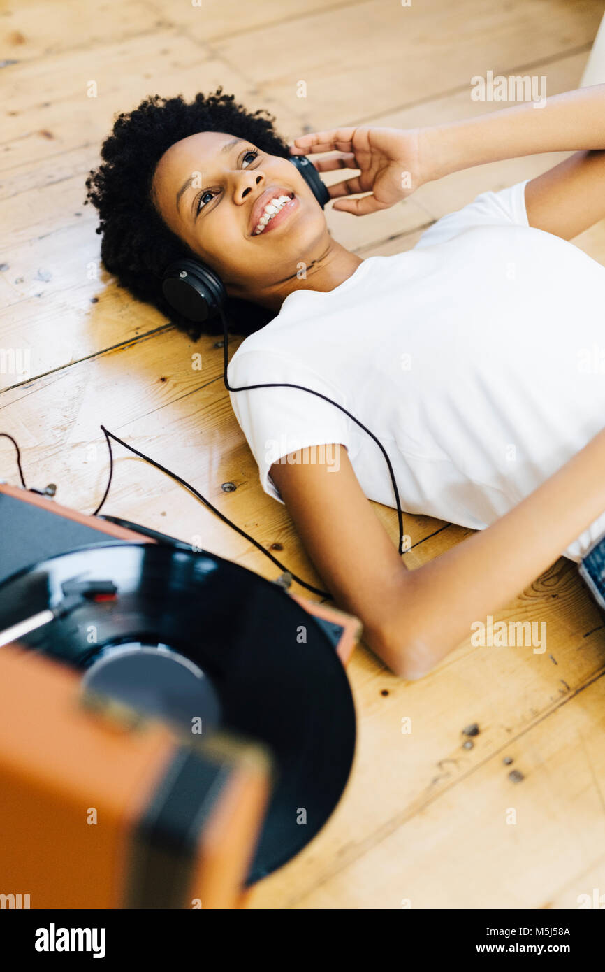 Jeune femme à la maison écouter les disques vinyles, étendue sur le sol Banque D'Images