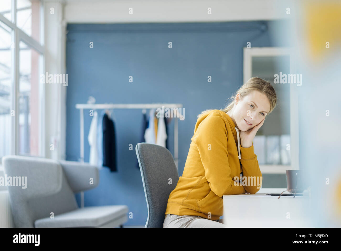 Portrait of Fashion designer sitting at desk in her Studio Banque D'Images