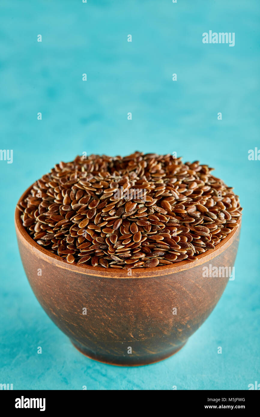 Narural matières graines de lin dans un bol d'argile céramique isolé sur fond bleu, close-up. Et utiles pour la cuisine de tous les jours d'oléagineux nutritionnel.Healthy Eatin'M Banque D'Images