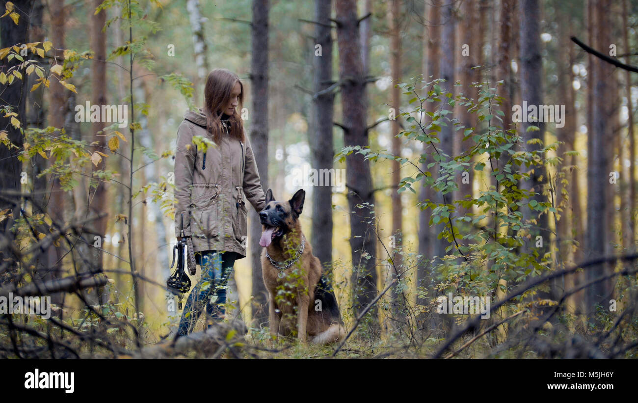 Jeune fille attirante et son animal de compagnie - berger allemand - marche sur une forêt d'automne Banque D'Images