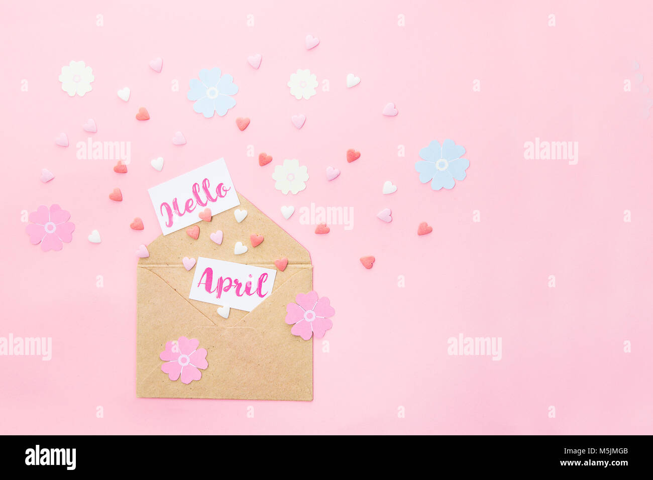 Bonbons multicolores bonbons coeur de sucre, tricot fleurs en papier et les cartes avec Bonjour lettrage avril l'avion à partir d'enveloppe de papier craft sur fond rose Banque D'Images