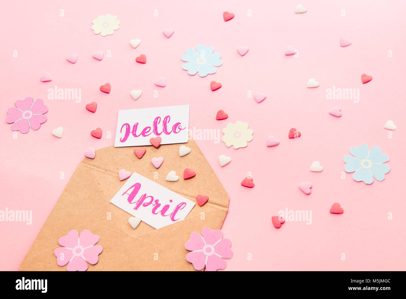 Bonbons multicolores bonbons coeur de sucre, tricot fleurs en papier et les cartes avec Bonjour lettrage avril l'avion à partir d'enveloppe de papier craft sur fond rose Banque D'Images