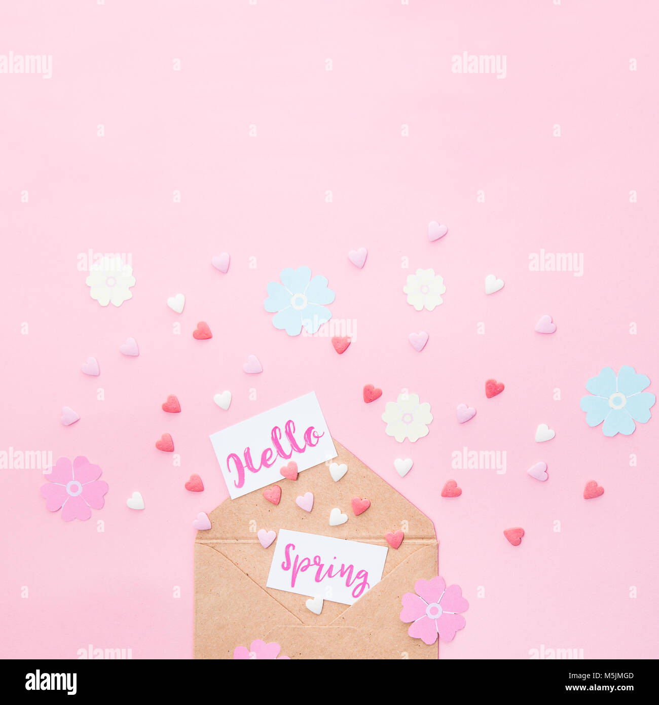 Bonbons multicolores bonbons coeur de sucre, tricot fleurs en papier et les cartes avec Bonjour lettrage printemps l'avion à partir d'enveloppe de papier craft sur fond rose Banque D'Images