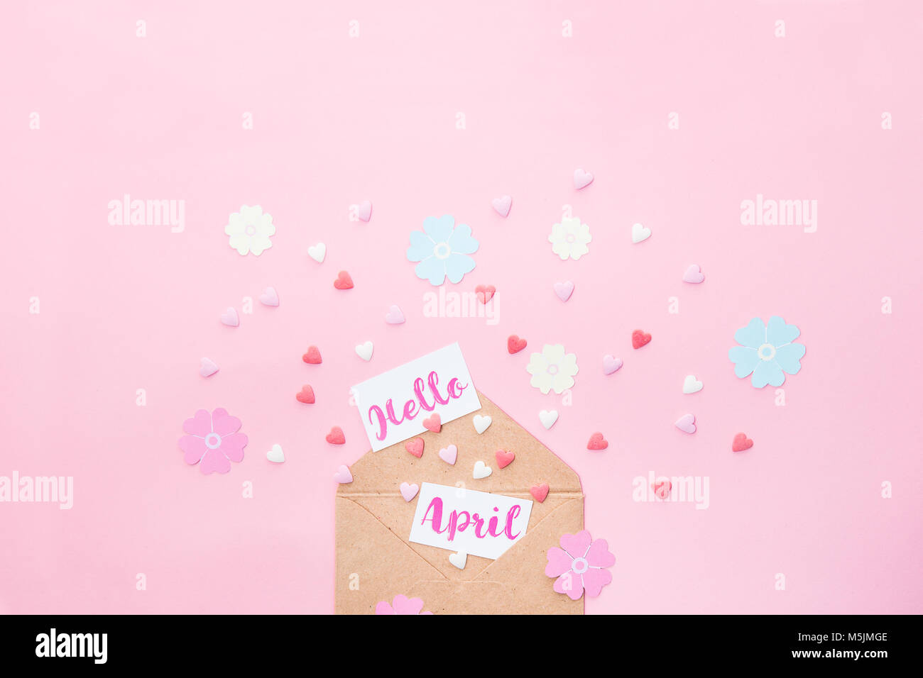 Bonbons multicolores bonbons coeur de sucre, tricot fleurs en papier et les cartes avec Bonjour lettrage avril l'avion à partir d'enveloppe de papier craft sur fond rose Banque D'Images