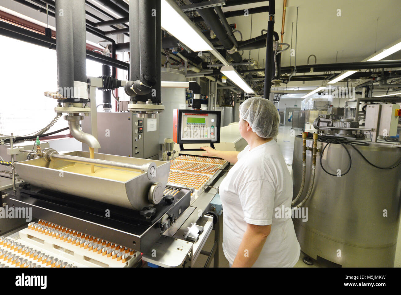 Production de pralines dans une usine pour l'industrie alimentaire - travailleur de la courroie du convoyeur avec du chocolat Banque D'Images