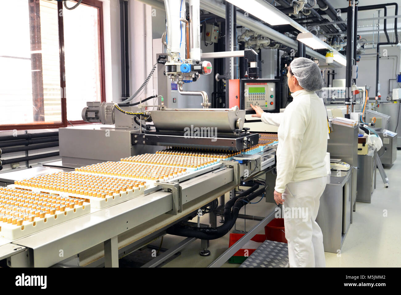 Production de pralines dans une usine pour l'industrie alimentaire - travailleur de la courroie du convoyeur avec du chocolat Banque D'Images